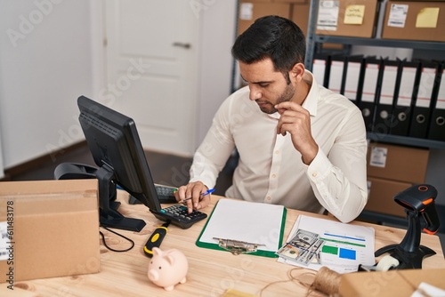 Young hispanic man e-commerce business worker doing account at office