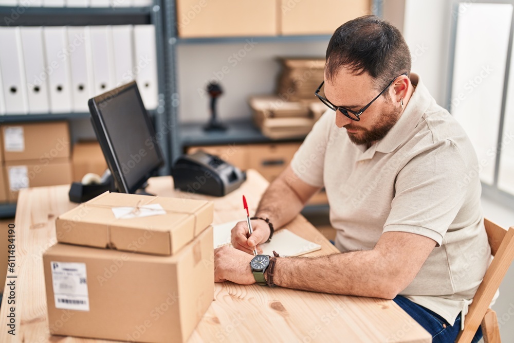 Young hispanic man e-commerce business worker writing on notebook at office Young hispanic man e-commerce business worker writing on notebook at office