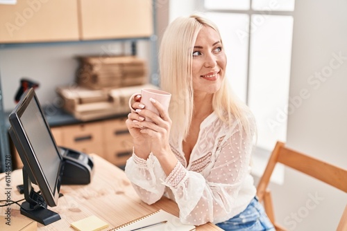 Young blonde woman ecommerce business worker drinking coffee at office