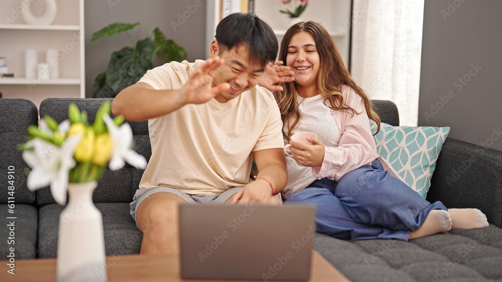 Man and woman couple sitting on sofa having video call drinking coffee at home Man and woman couple sitting on sofa having video call drinking coffee at home