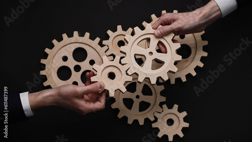 Group of business people connecting wooden cogwheels together. Office colleagues joining gears in chain.