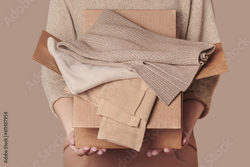 Woman holding cardboard box with used clothes wardrobe, ready to give away. Circular fashion, fast fashion, clothing recycling, eco friendly sustainable shopping, resale, thrift stores concept