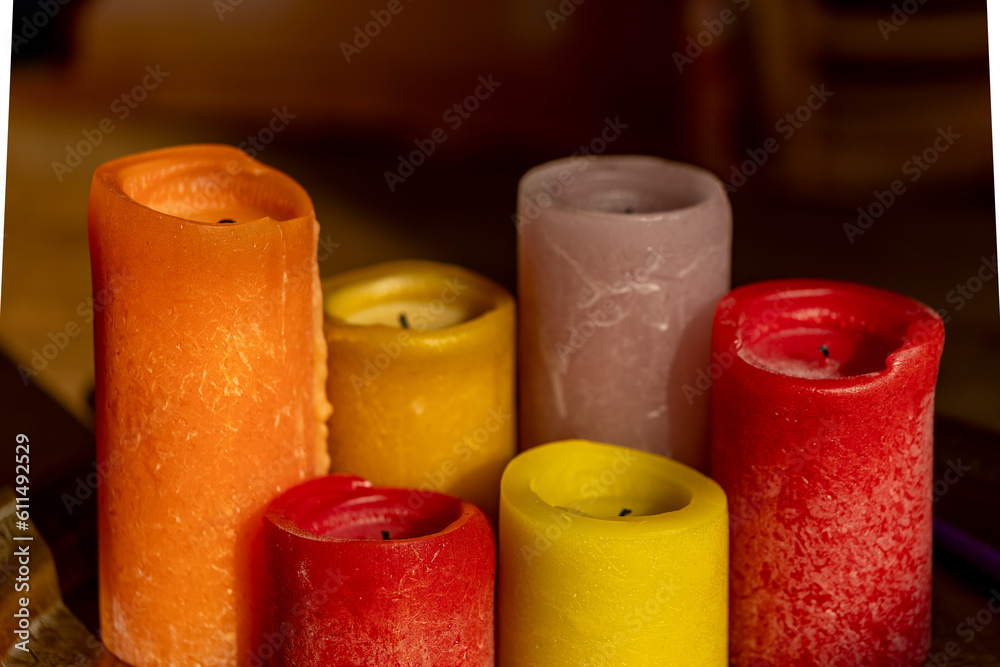 Couple of different sized coloured candles against abstract cafe background on wooden table. Moody lit up wax candles Couple of different sized coloured candles against abstract cafe background on wooden table. Moody lit up wax candles