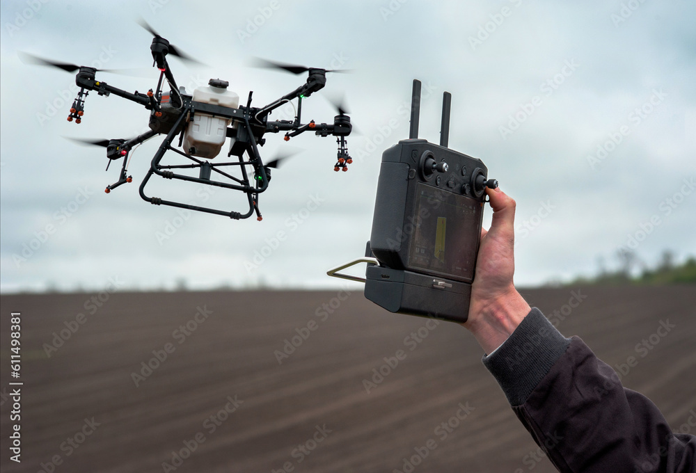 Male hands hold the remote control of an agricultural sprayer drone