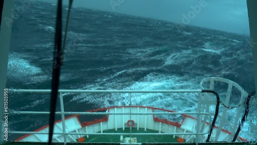 Ship in storm. Splashes from waves on window of wheelhouse. Window wiper is working. Strong pitching. White foam. photo