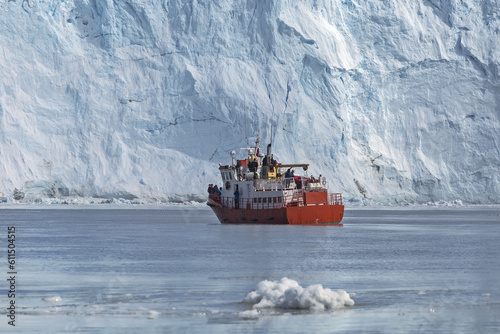 Red cruise boat in front of the glacier in Greenland