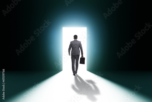 Businessman entering backlit door in escape concept photo