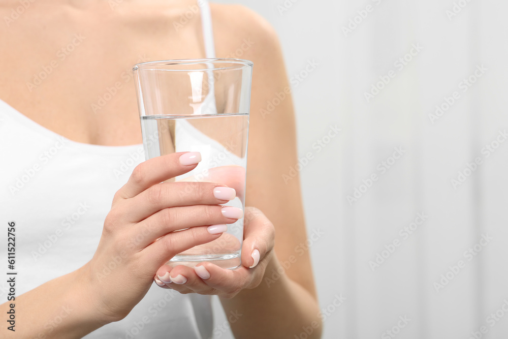 Healthy habit. Closeup of woman holding glass with fresh water indoors, space for text Healthy habit. Closeup of woman holding glass with fresh water indoors, space for text
