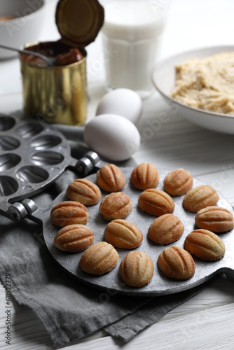 Delicious walnut shaped cookies with condensed milk and ingredients on white wooden table, closeup © New Africa