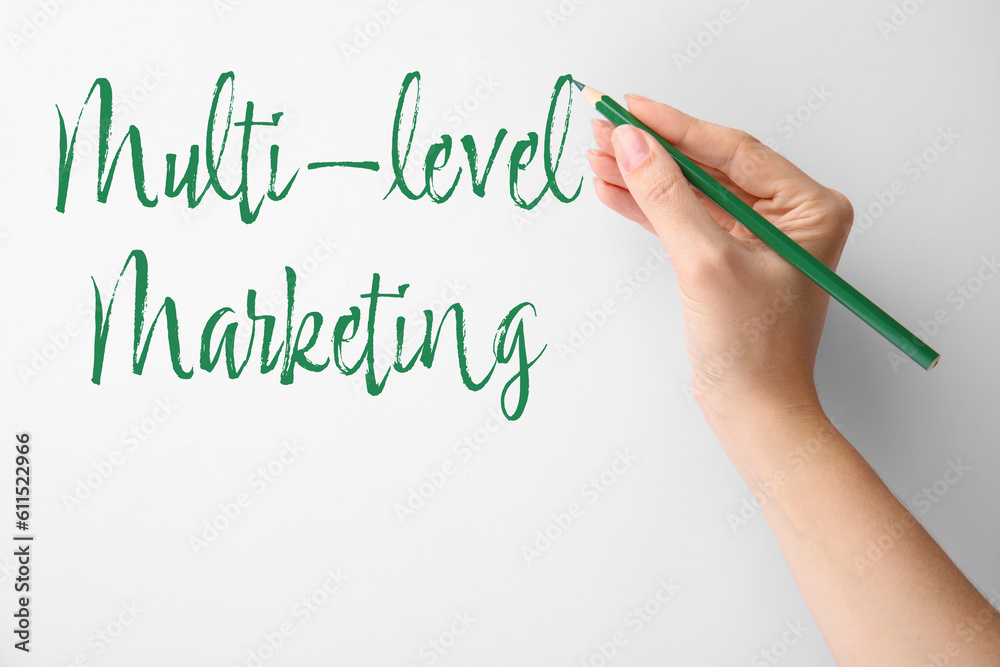 Woman writing text Multi Level Marketing on white background, closeup