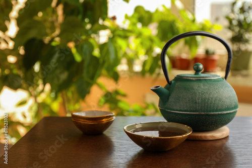 Teapot and cup of freshly brewed tea on wooden table indoors, space for text. Traditional ceremony