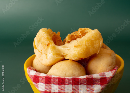 Cheese bread (Brazilian pao de queijo mineiro), close up view, on a bowl, green background, copy space for text photo