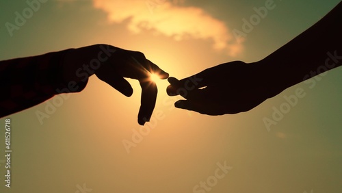 Gentle touch with fingers of hands in sunset. Finger Touching hands, silhouette of man, woman in sun, couple feels love. Reunion of loved ones, family happiness. Black hands touching each other. Sky
