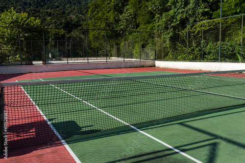 View of a green and red tennis court with nature all around. Widely used for sports and playing tennis © Diego