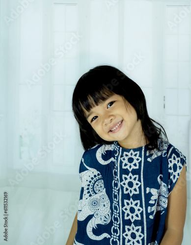 The portrait of a little child girl stands smiling looking into the camera's