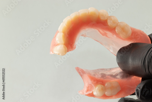 Woman holding a broken lower complete denture. Selective focus.