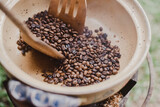 a wooden spoon is scooping coffee beans into a bowl of coffee beans on a stove top burner