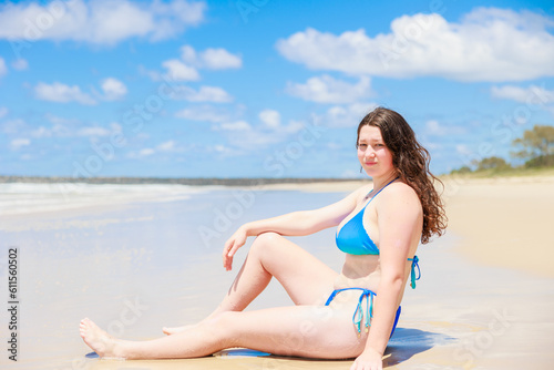 ビーチに座るセクシーな水着姿の白人の女の子