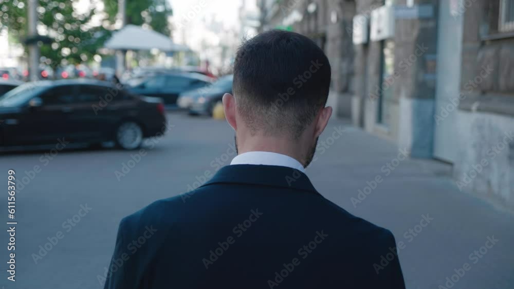 Back view confident business man walking away from camera along city center street at downtown. Rear back view walking business man wearing suit commuting to work. Business person walking on street Back view confident business man walking away from camera along city center street at downtown. Rear back view walking business man wearing suit commuting to work. Business person walking on street