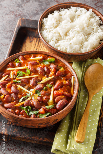 Rajma masala is a Indian vegetarian dish consisting of red kidney beans in a thick gravy with many spices served with rice close-up on a wooden tray on the table. Vertical