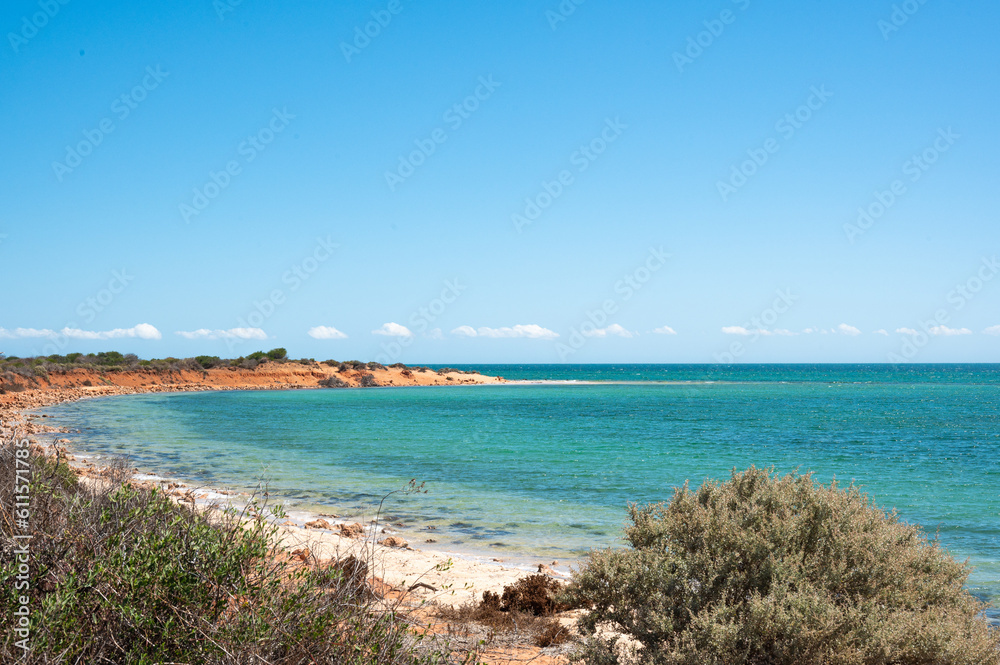 view of the sea from the beach, red orange sand and turquoise water. Shark bay Australia