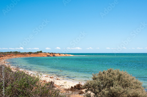 view of the sea from the beach, red orange sand and turquoise water. Shark bay Australia