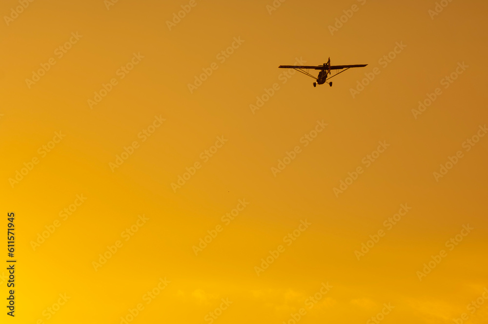 Ultralight plane silhouette in orange sky at sunset