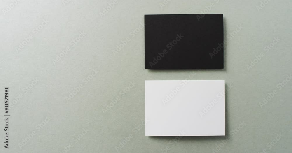 Close up of two stacks of black and white business cards on grey background, copy space, slow motion Close up of two stacks of black and white business cards on grey background, copy space, slow motion