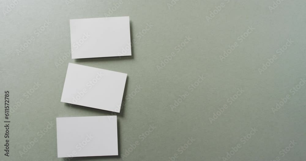 Overhead view of three white business cards arranged on grey background, copy space, slow motion Overhead view of three white business cards arranged on grey background, copy space, slow motion