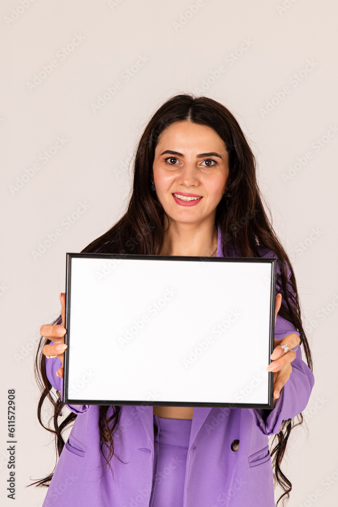 Naklejka premium Beautiful young woman holding empty blank white board, your text here concept. Smile Business woman portrait with blank white banner