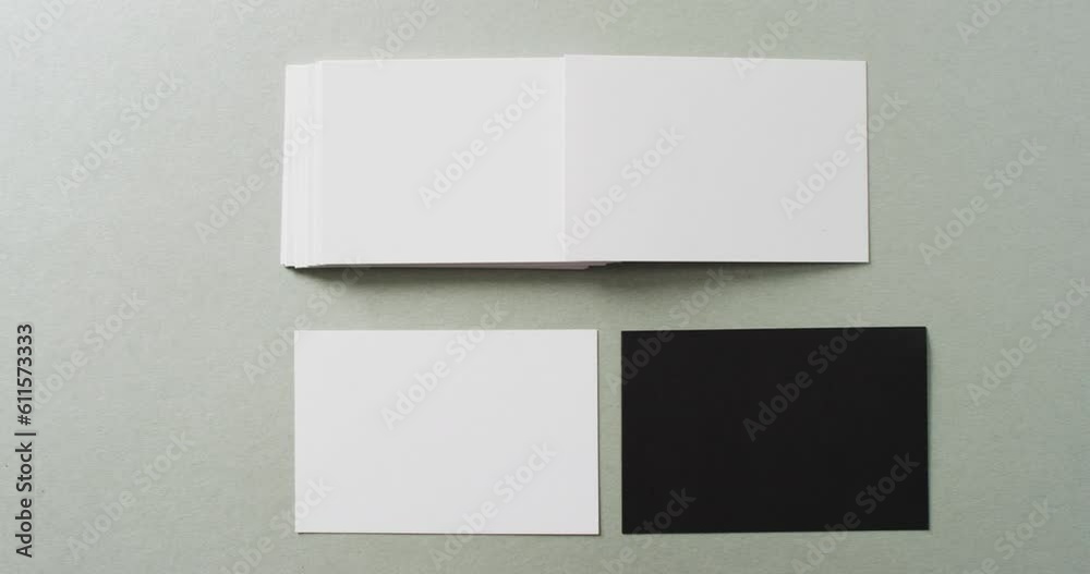 Overhead view of blank white and black business cards on grey background, copy space, slow motion Overhead view of blank white and black business cards on grey background, copy space, slow motion
