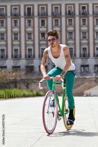 Bicycle, fitness and young man in city for travel and carbon footprint, gen z streetwear and casual fashion. Cool person or student in sunglasses and bike transport for exercise at campus building