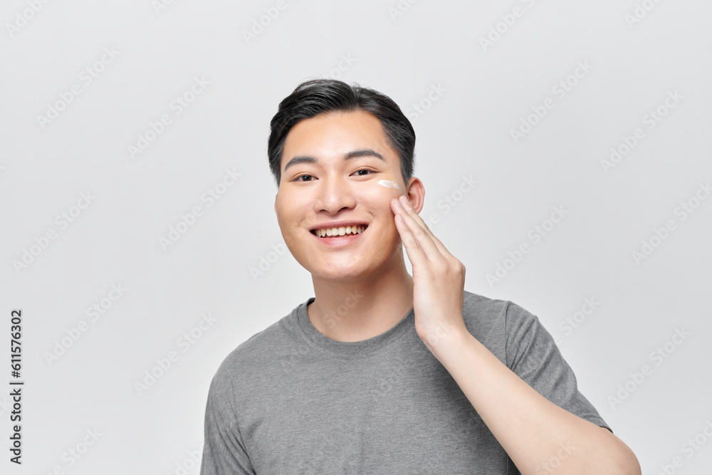 Close up beauty portrait of half naked satisfied young man applying facial cream Close up beauty portrait of half naked satisfied young man applying facial cream