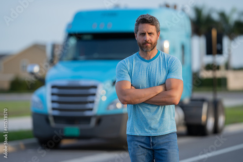 Men driver near lorry truck. Man owner truck driver in t-shirt near truck. Handsome middle aged man trucker trucking owner. Semi trailer, semi trucks. Handsome man posing in front of truck.