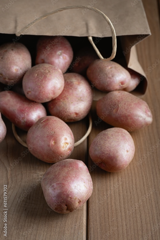 New raw red potatoes in paper bag on wooden background New raw red potatoes in paper bag on wooden background