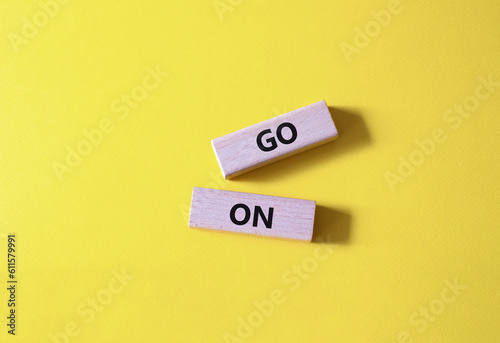 Go on symbol. Wooden blocks with words Go on. Beautiful yellow background. Business and Go on concept. Copy space.