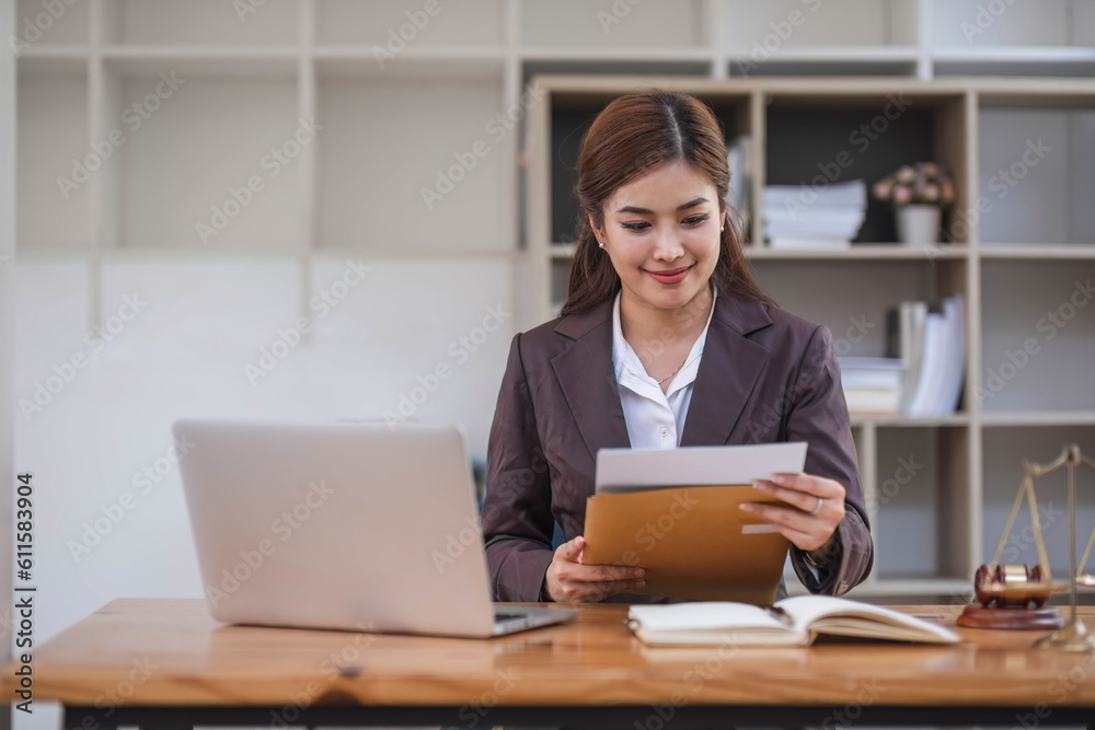 Looking camera. Young Attractive Asian female lawyer working in office with contract and law books when sitting at desk. Law, legal services, advice, Justice and real estate concept. Looking camera. Young Attractive Asian female lawyer working in office with contract and law books when sitting at desk. Law, legal services, advice, Justice and real estate concept.