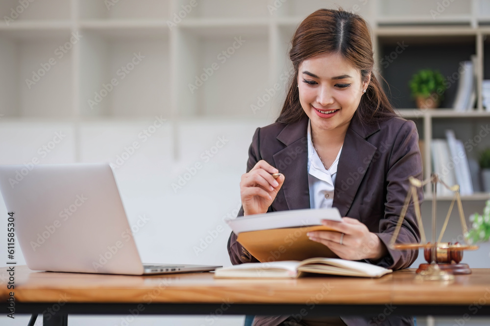 Looking camera. Young Attractive Asian female lawyer working in office with contract and law books when sitting at desk. Law, legal services, advice, Justice and real estate concept.