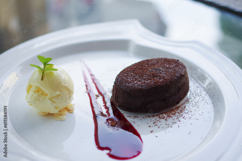 molten chocolate cake and vanilla ice cream ball with almond slices on white plate molten chocolate cake and vanilla ice cream ball with almond slices on white plate