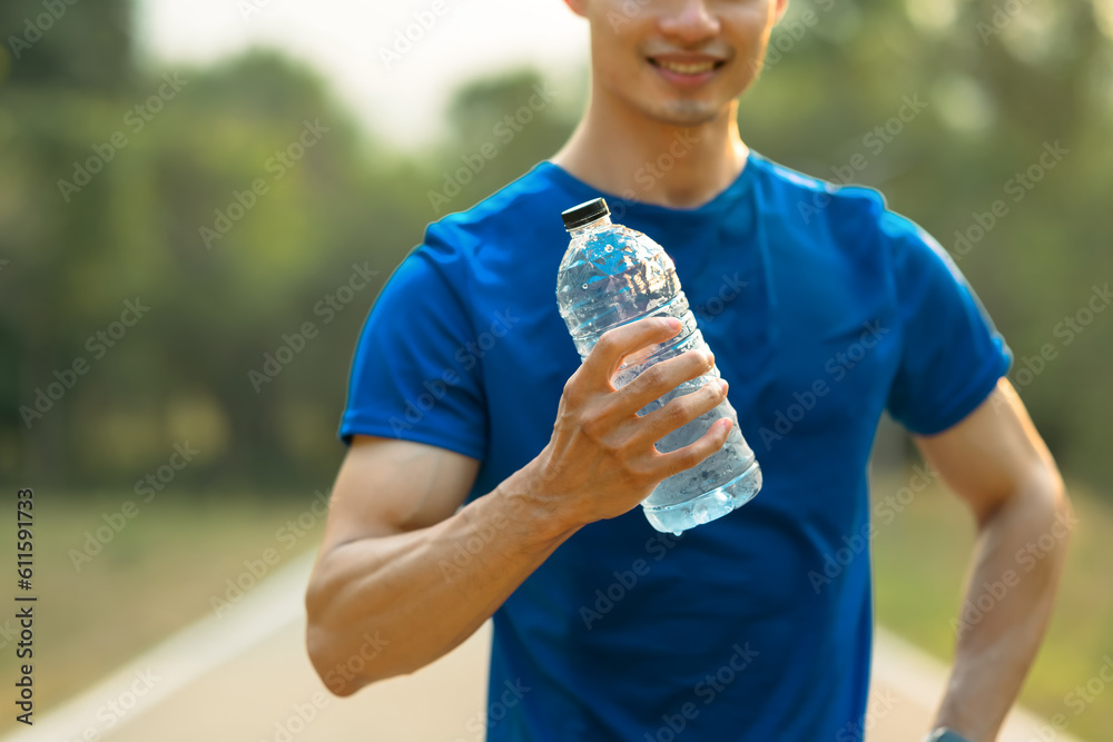 Sportsman holding a bottle of water, resting after workout session outdoor. Fitness, training and healthy lifestyle Sportsman holding a bottle of water, resting after workout session outdoor. Fitness, training and healthy lifestyle
