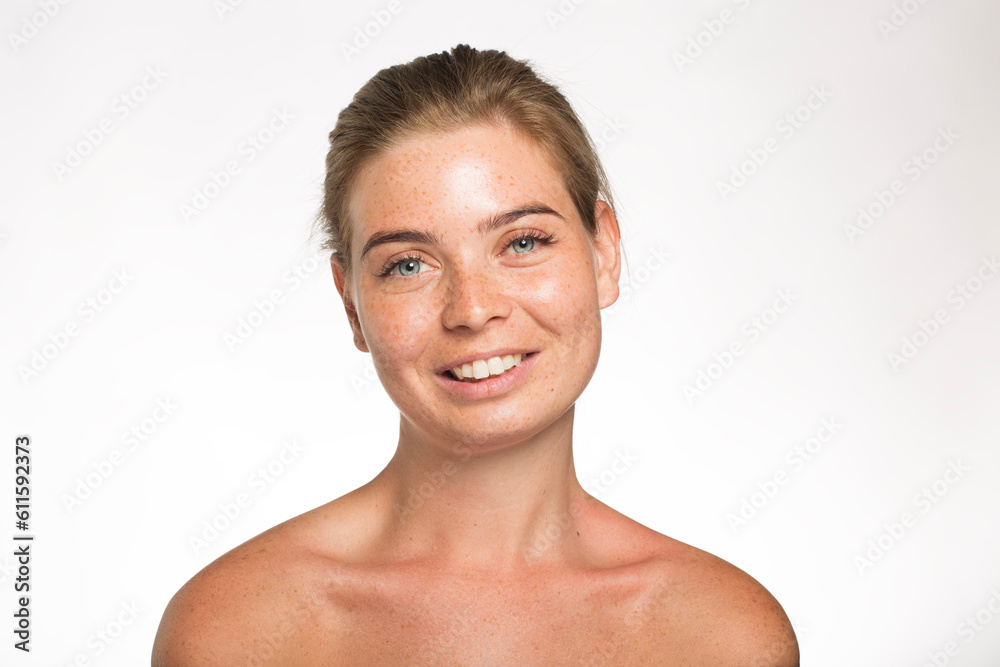 Beautiful girl with freckles look at the camera with her hair tied up in front of the camera on a white background Beautiful girl with freckles look at the camera with her hair tied up in front of the camera on a white background