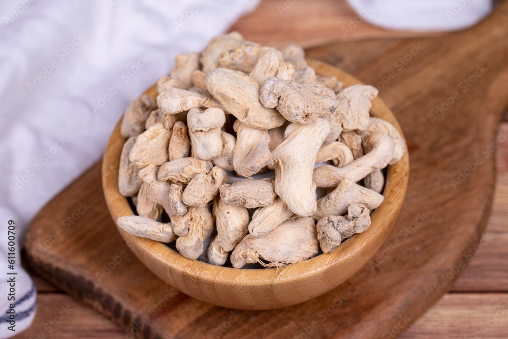 Dried Organic Ginger root on wooden background. Sun-dried ginger root or Dry Adrak in wooden bowl Dried Organic Ginger root on wooden background. Sun-dried ginger root or Dry Adrak in wooden bowl