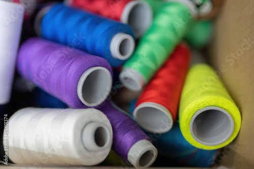 Spools of thread come in a variety of colors, green, purple, white, yellow, blue and red, in a cardboard box. beautiful eye-catching colors for weaving in the sewing industry