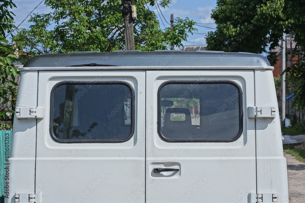 back of an old minibus with two windows on a white door on the street