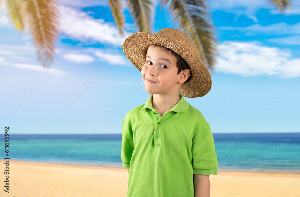 Child on vacation wearing green t-shirt hat at tropical beach happy face smiling looking at the camera. Positive person