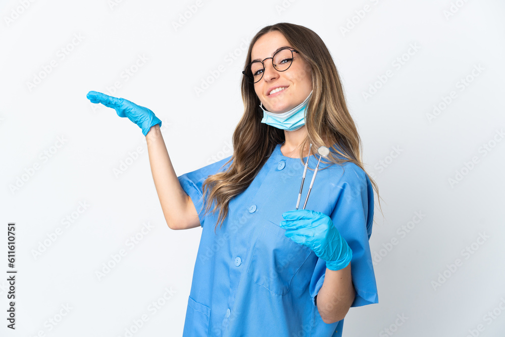 Woman Romanian dentist holding tools over isolated on pink background extending hands to the side for inviting to come Woman Romanian dentist holding tools over isolated on pink background extending hands to the side for inviting to come