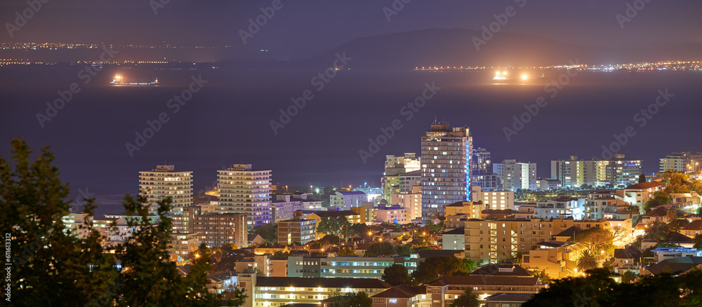 Harbour, buildings and city at night with lights, urban development and streets. Dark, travel and outdoor residential architecture of downtown with ocean or sea water in the evening with a skyline.