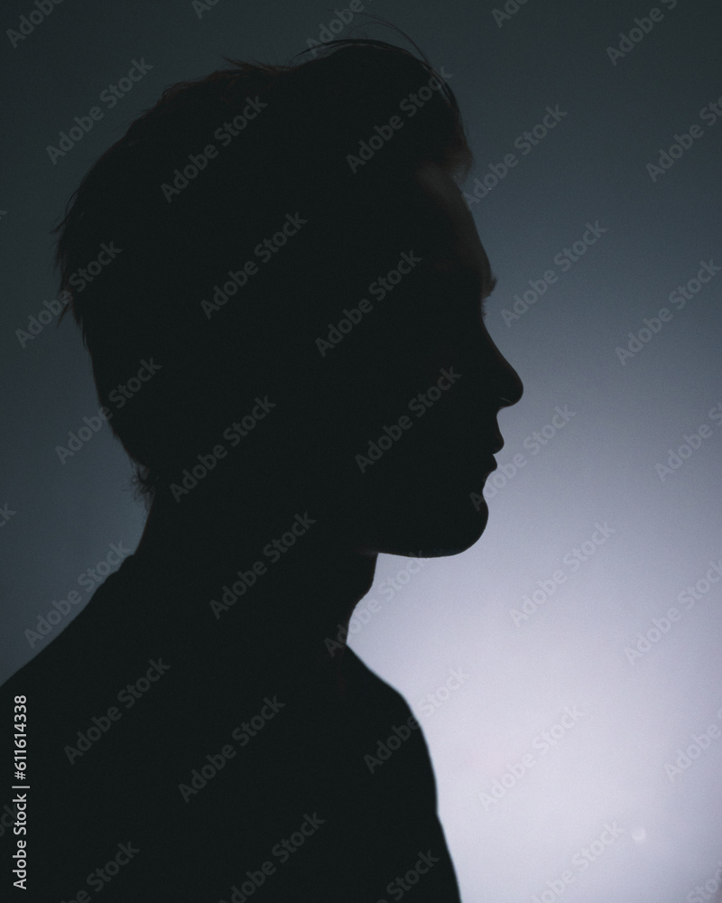 A silhouette of a man deep in thought in a dark room A silhouette of a man deep in thought in a dark room