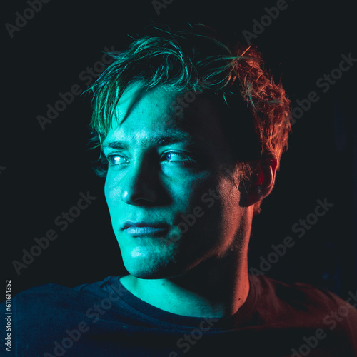 Creative orange and teal light portrait shots of a man in a dark room