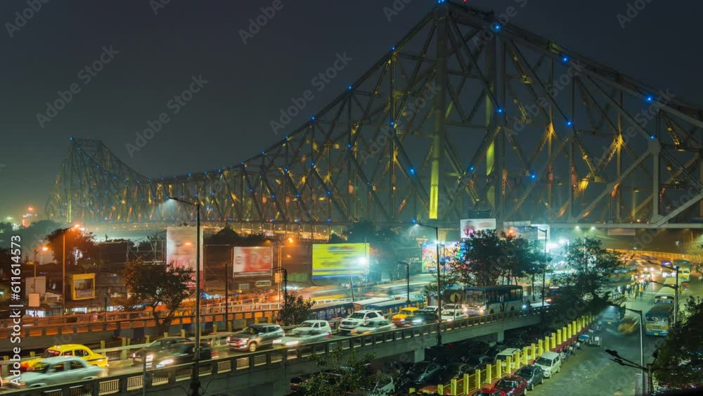Timelapse view of traffic exiting architectural landmark Howrah Bridge illuminated at night in Kolkata, West Bengal, India.